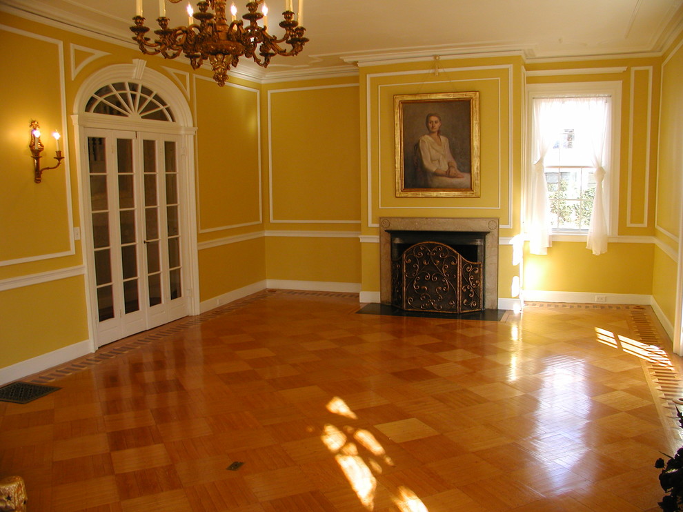 Пример оригинального дизайна: большая парадная, открытая гостиная комната в классическом стиле с желтыми стенами, паркетным полом среднего тона, стандартным камином и фасадом камина из камня
