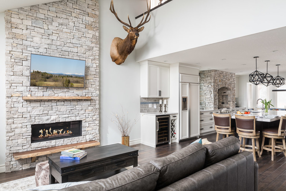 Example of a mid-sized trendy open concept dark wood floor and brown floor living room design in Calgary with gray walls, a ribbon fireplace, a stone fireplace and a wall-mounted tv