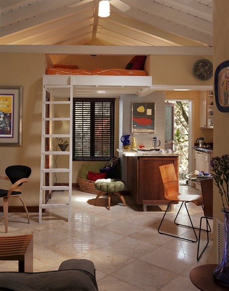 Immagine di un soggiorno tropicale di medie dimensioni e stile loft con libreria, pareti beige, pavimento in marmo e TV a parete