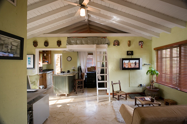 Immagine di un soggiorno tropicale di medie dimensioni e stile loft con sala della musica, pareti verdi, pavimento in marmo e TV a parete