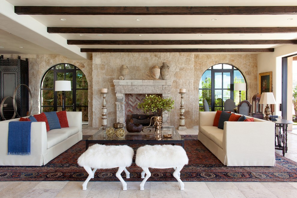 Идея дизайна: гостиная комната в средиземноморском стиле с фасадом камина из камня, бежевыми стенами и стандартным камином