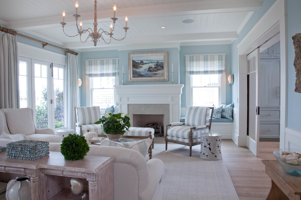 Réalisation d'un salon marin ouvert avec une salle de réception, un mur bleu, un sol en bois brun, une cheminée standard et un manteau de cheminée en pierre.
