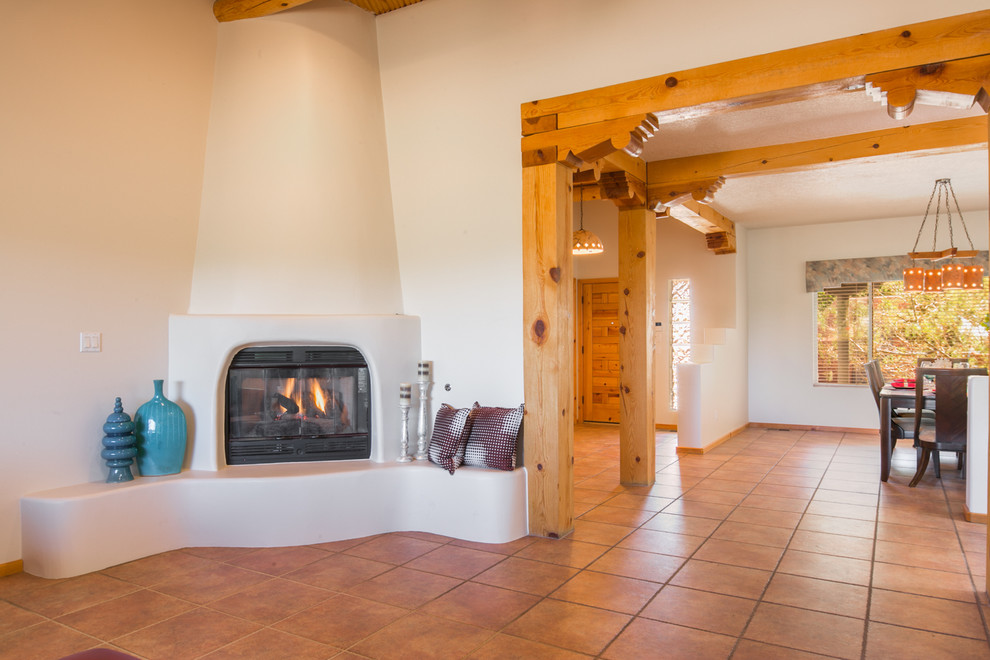 Inspiration for a large southwestern open concept ceramic tile living room remodel in Albuquerque with white walls, a corner fireplace and a plaster fireplace