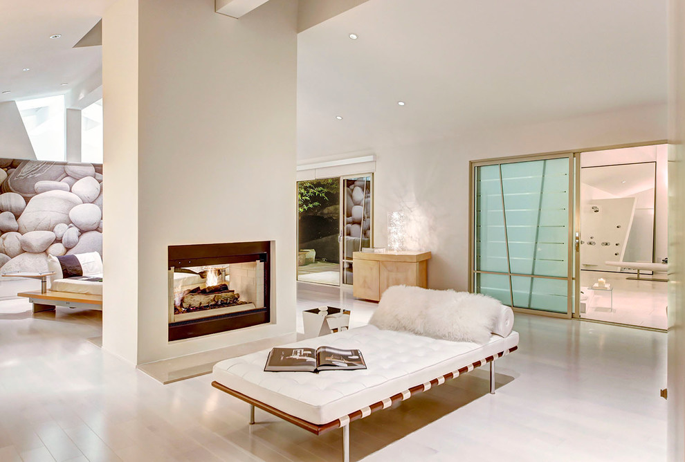 Immagine di un soggiorno design aperto con parquet chiaro, camino bifacciale e pareti bianche