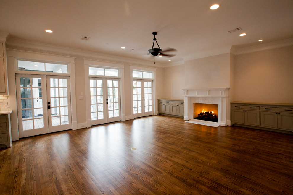 Cette image montre un salon craftsman ouvert avec un mur beige, un sol en bois brun, une cheminée standard et un manteau de cheminée en carrelage.