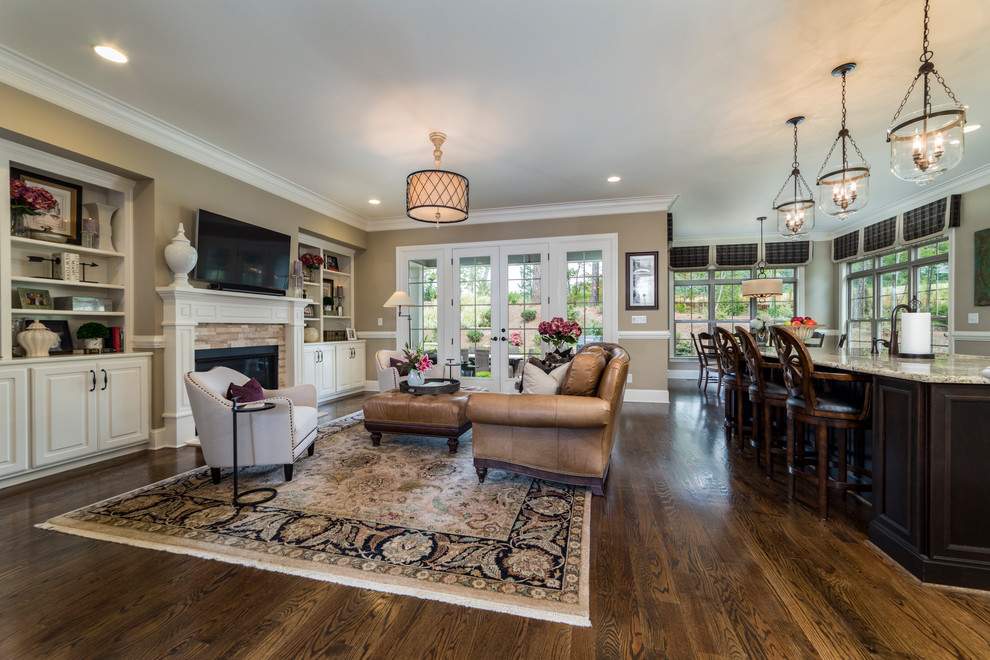 This is an example of a large traditional open plan living room in Raleigh with brown walls, dark hardwood flooring, a standard fireplace, a tiled fireplace surround, a wall mounted tv and brown floors.