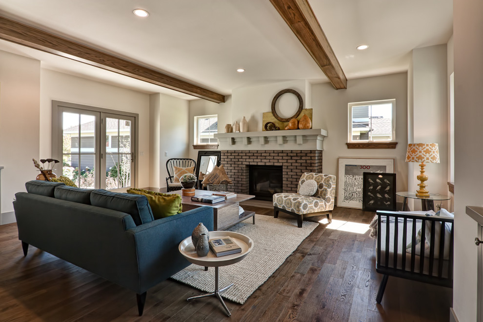 Стильный дизайн: гостиная комната в классическом стиле с стандартным камином, фасадом камина из кирпича, коричневым полом и синим диваном без телевизора - последний тренд