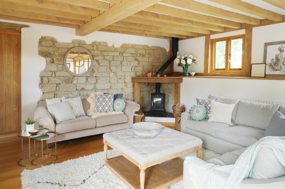 Idee per un soggiorno country con pareti bianche, pavimento in legno massello medio, stufa a legna e tappeto