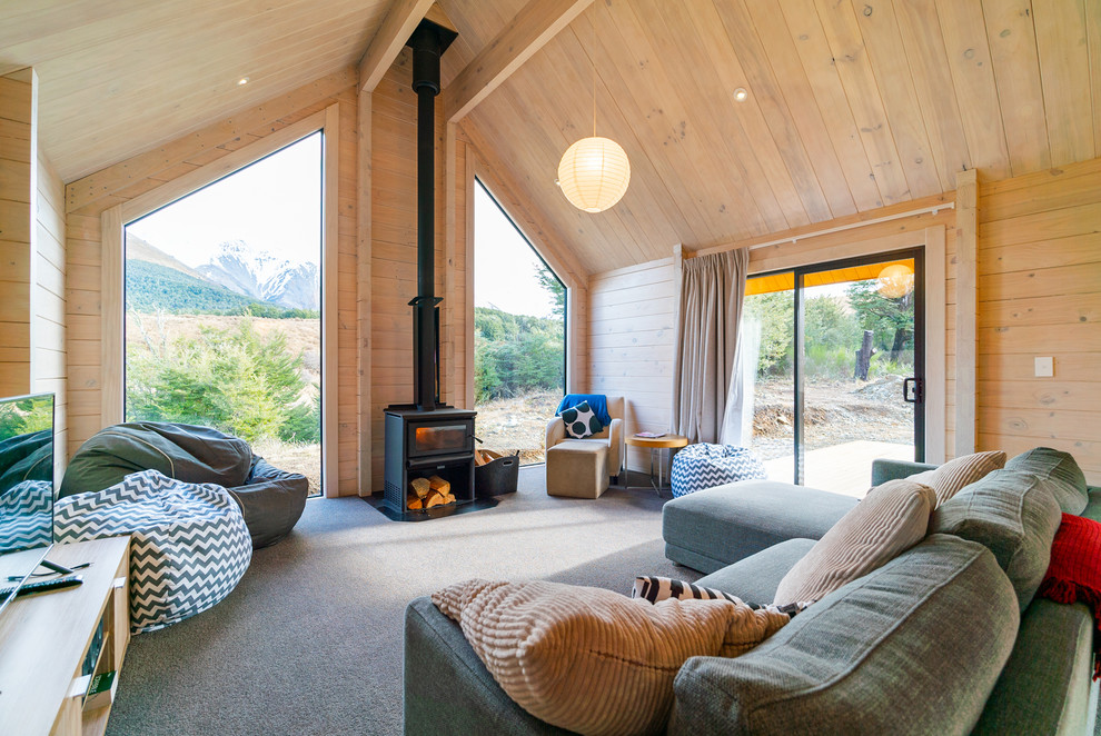 Imagen de salón abierto rural de tamaño medio con moqueta, estufa de leña, marco de chimenea de madera, suelo gris y paredes marrones