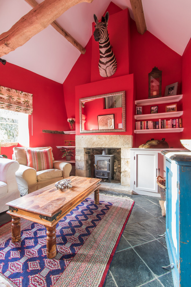 Ejemplo de salón cerrado ecléctico sin televisor con paredes rojas, suelo de pizarra, estufa de leña y marco de chimenea de piedra