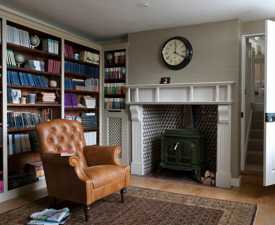 Esempio di un soggiorno country di medie dimensioni e chiuso con libreria, pareti beige, pavimento in legno massello medio, stufa a legna e nessuna TV