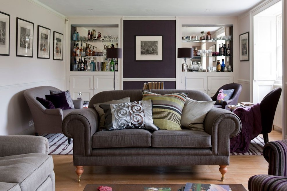 Example of a mid-sized country enclosed medium tone wood floor living room design in London with a bar, beige walls, a standard fireplace, a plaster fireplace and no tv