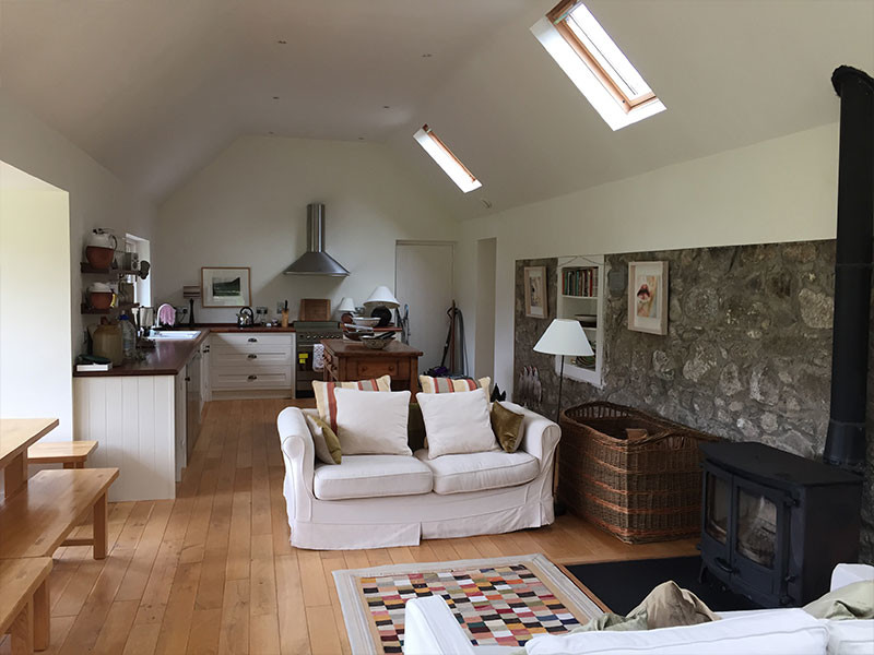 Photo of a medium sized farmhouse living room in Dublin with a wood burning stove and a stone fireplace surround.