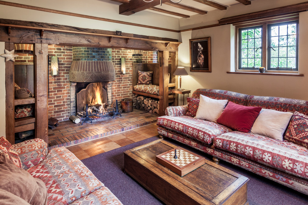 Mittelgroßes Landhausstil Wohnzimmer mit braunem Holzboden, Kamin, Kaminumrandung aus Backstein, braunem Boden und weißer Wandfarbe in Hertfordshire