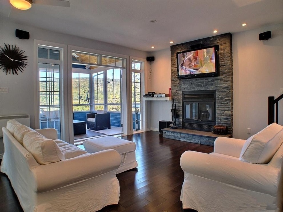 This is an example of a large contemporary open plan living room in Montreal with grey walls, dark hardwood flooring, a standard fireplace, a stone fireplace surround and a wall mounted tv.