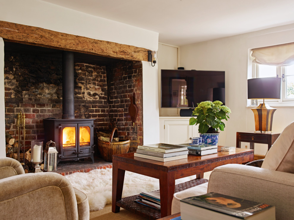 Exemple d'un salon nature avec un mur blanc, un poêle à bois, un manteau de cheminée en brique et un téléviseur d'angle.