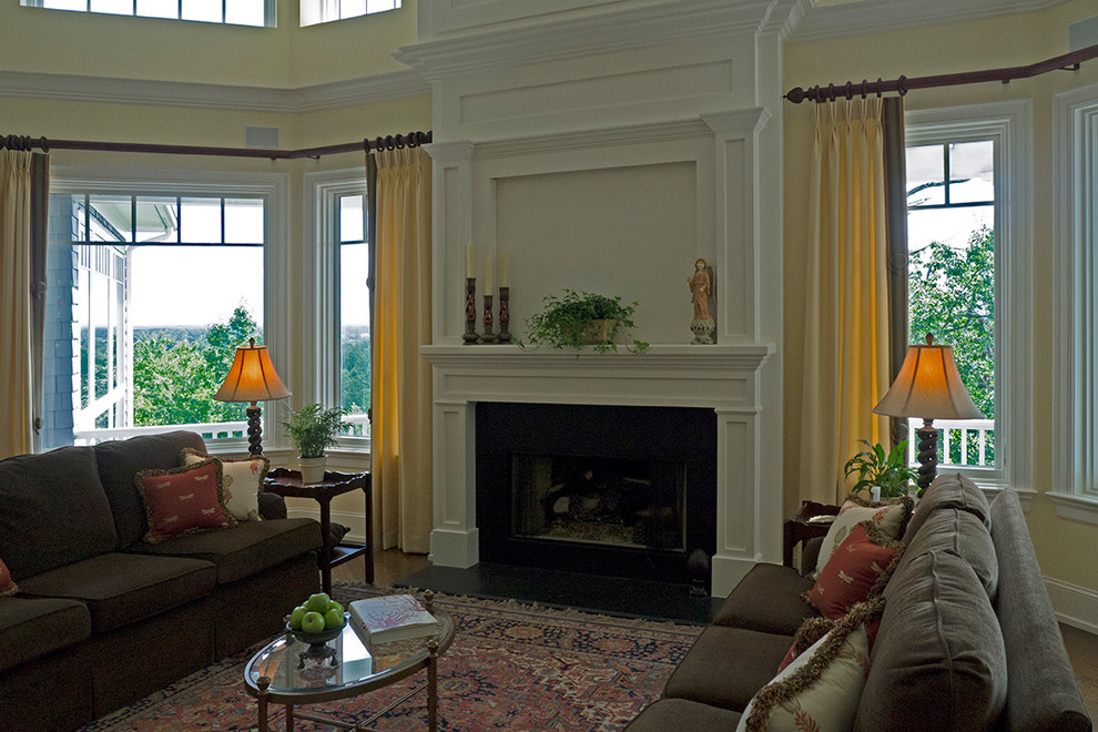 Immagine di un soggiorno tradizionale con sala formale, pareti gialle, camino classico, cornice del camino in mattoni, TV nascosta e parquet chiaro