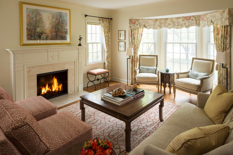 Cette image montre un salon traditionnel avec une salle de réception, un mur beige, un sol en bois brun, une cheminée standard et un manteau de cheminée en carrelage.