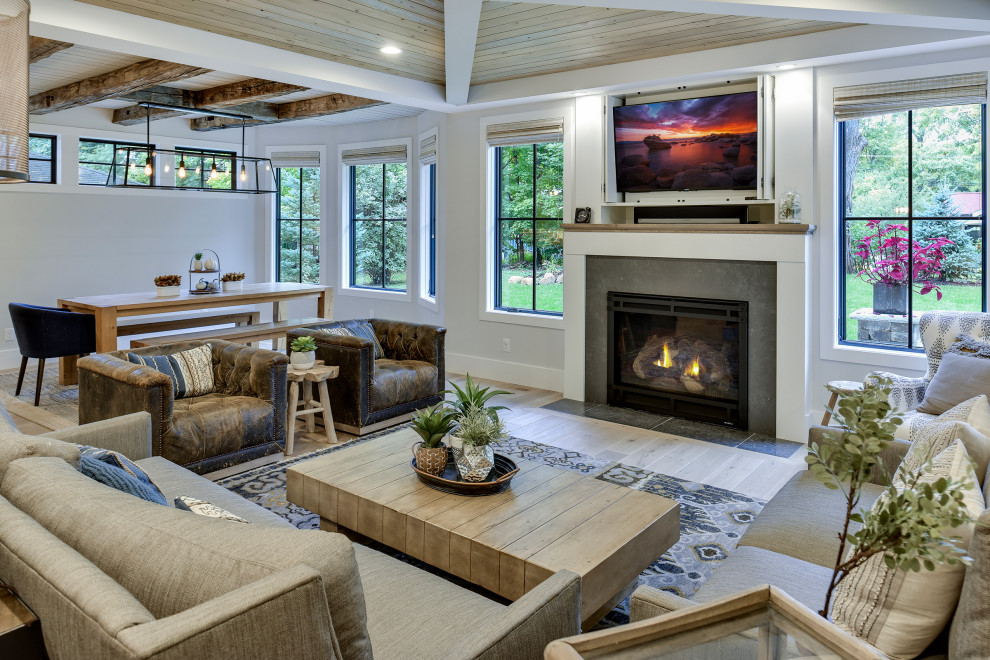 Cette image montre un salon rustique de taille moyenne et ouvert avec un mur blanc, un sol en bois brun, une cheminée standard, un manteau de cheminée en béton, un téléviseur dissimulé et un sol marron.