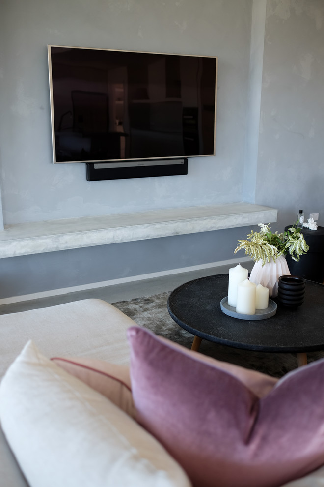 Idee per un soggiorno minimal di medie dimensioni e aperto con pareti grigie, pavimento in cemento, TV a parete e pavimento grigio