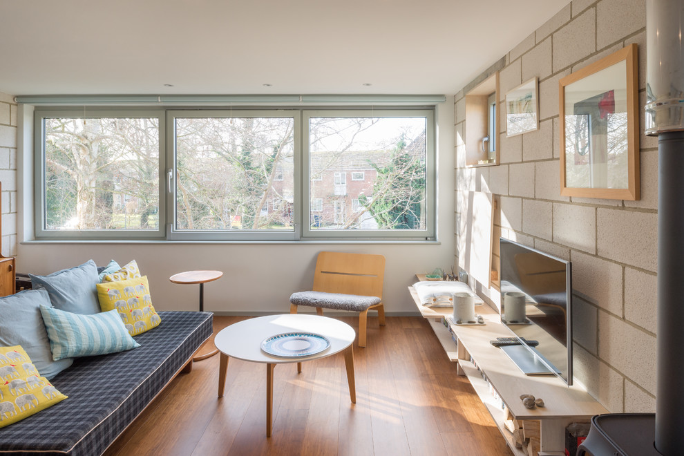 Inspiration for a scandi enclosed living room in Oxfordshire with beige walls, medium hardwood flooring, a hanging fireplace, a metal fireplace surround, a freestanding tv and brown floors.