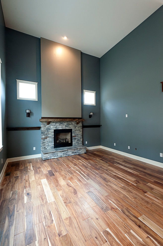 Exemple d'un salon montagne ouvert avec un mur bleu, un sol en bois brun, une cheminée standard et un manteau de cheminée en pierre.