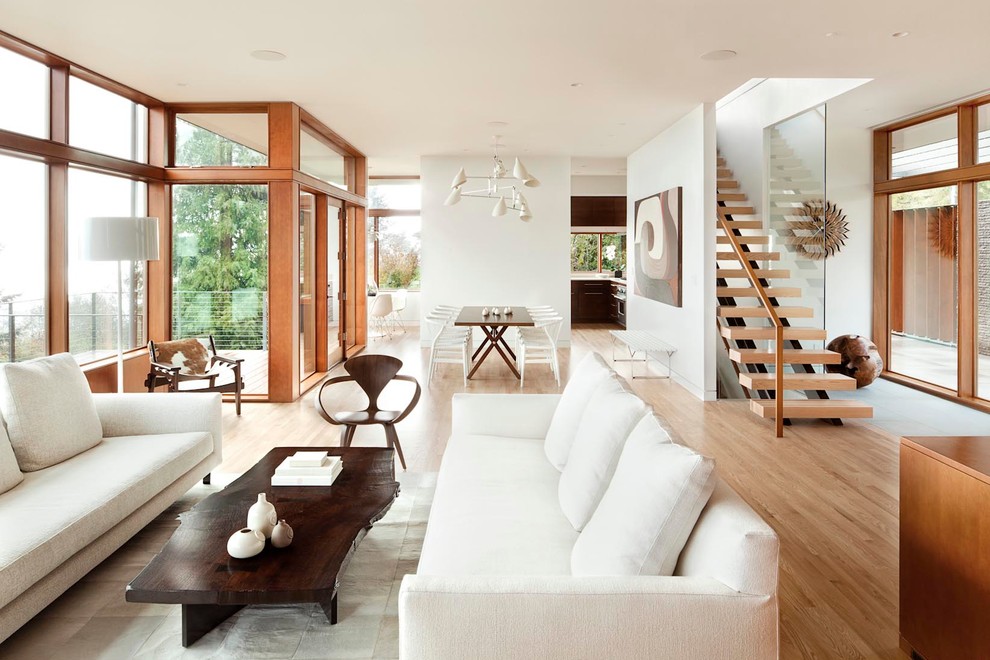 This is an example of a modern open plan living room in Portland with white walls and light hardwood flooring.