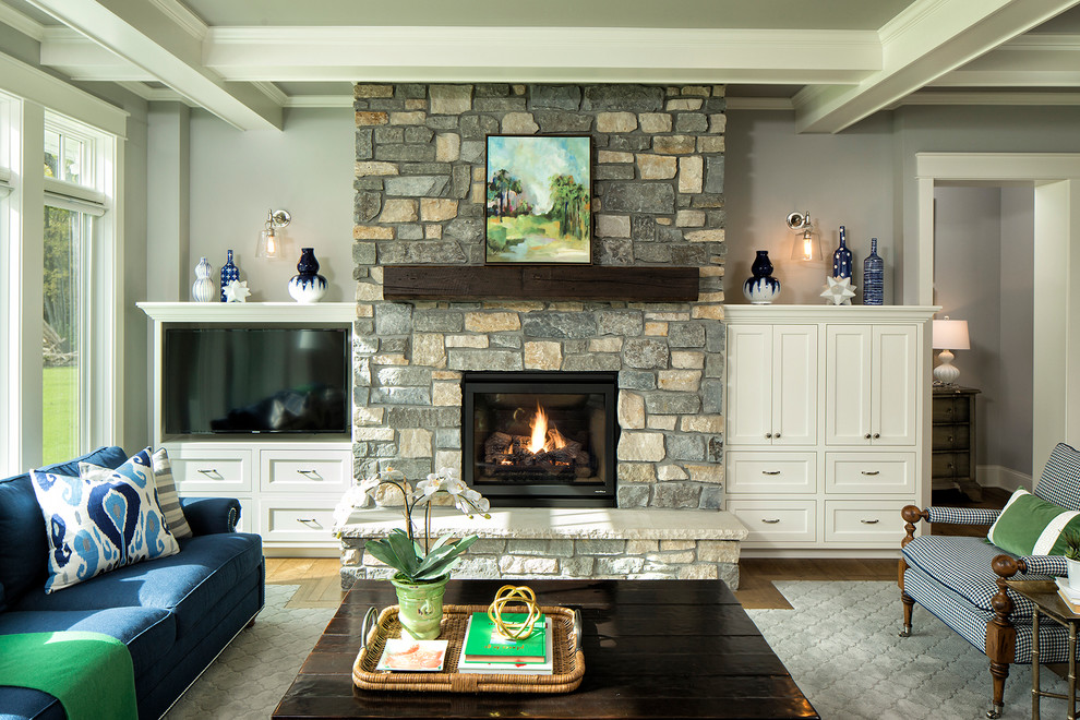 Aménagement d'un grand salon classique ouvert avec un sol en bois brun, une cheminée standard, un manteau de cheminée en pierre et un téléviseur encastré.