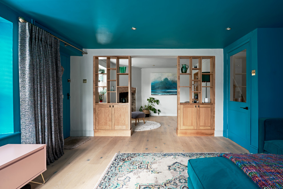 Réalisation d'un salon design de taille moyenne et ouvert avec un mur bleu, un sol en bois brun, une cheminée standard, un manteau de cheminée en pierre et un sol marron.
