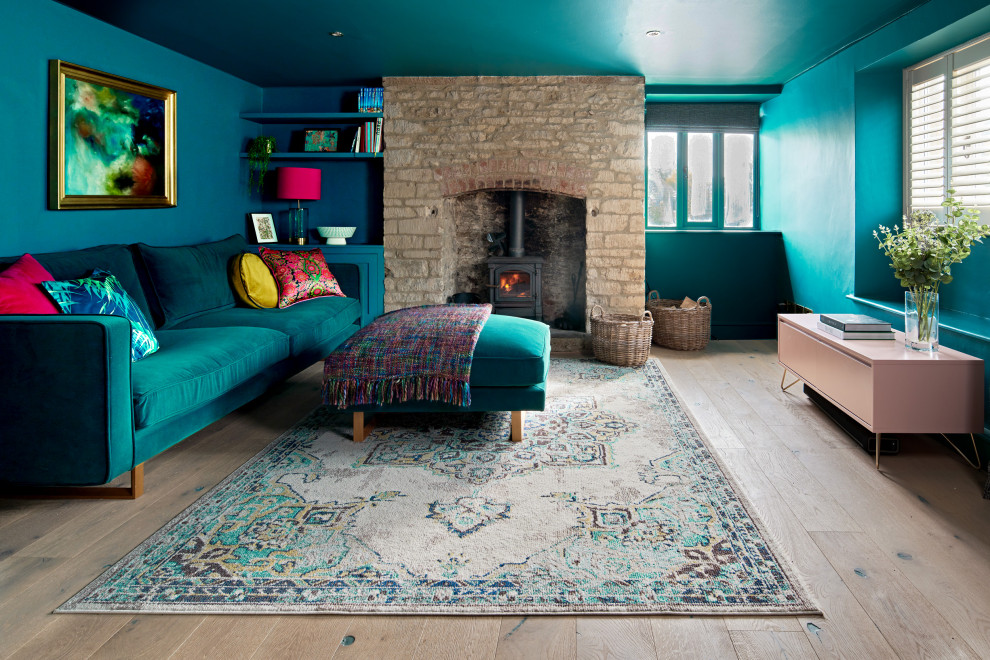 Стильный дизайн: открытая гостиная комната среднего размера в современном стиле с синими стенами, стандартным камином, фасадом камина из камня, паркетным полом среднего тона и коричневым полом - последний тренд