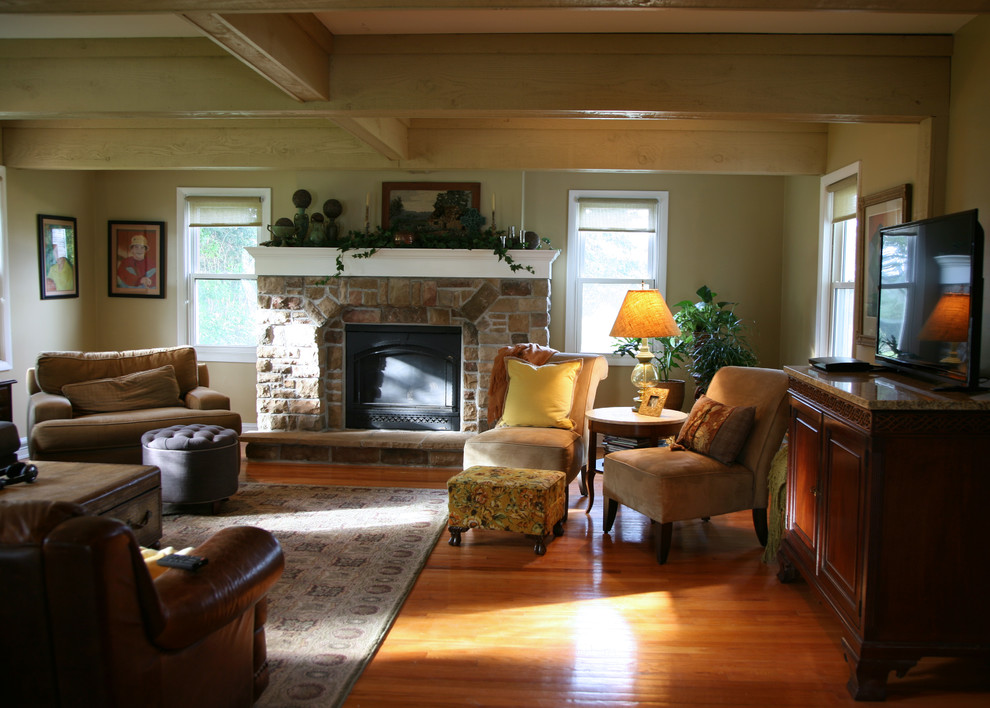Réalisation d'un salon champêtre de taille moyenne et ouvert avec un mur jaune, un sol en bois brun, une cheminée standard, un manteau de cheminée en pierre, un téléviseur dissimulé et un sol marron.