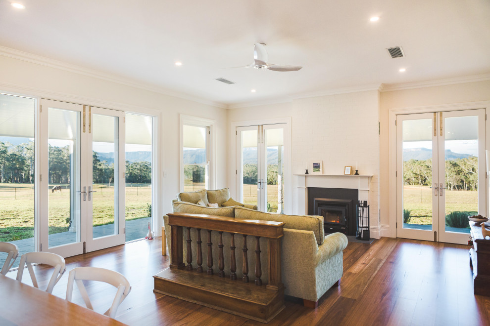 Imagen de salón abierto de estilo de casa de campo con paredes blancas, suelo de madera en tonos medios, todas las chimeneas y suelo marrón