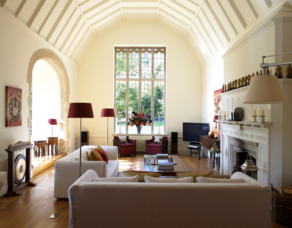Esempio di un grande soggiorno minimal con sala formale, pareti beige, pavimento in legno massello medio, camino classico e TV autoportante