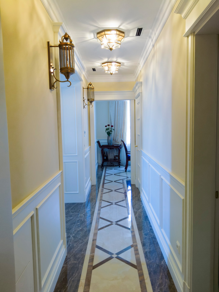 Réalisation d'un grand couloir victorien avec un mur beige, un sol en marbre et un sol beige.