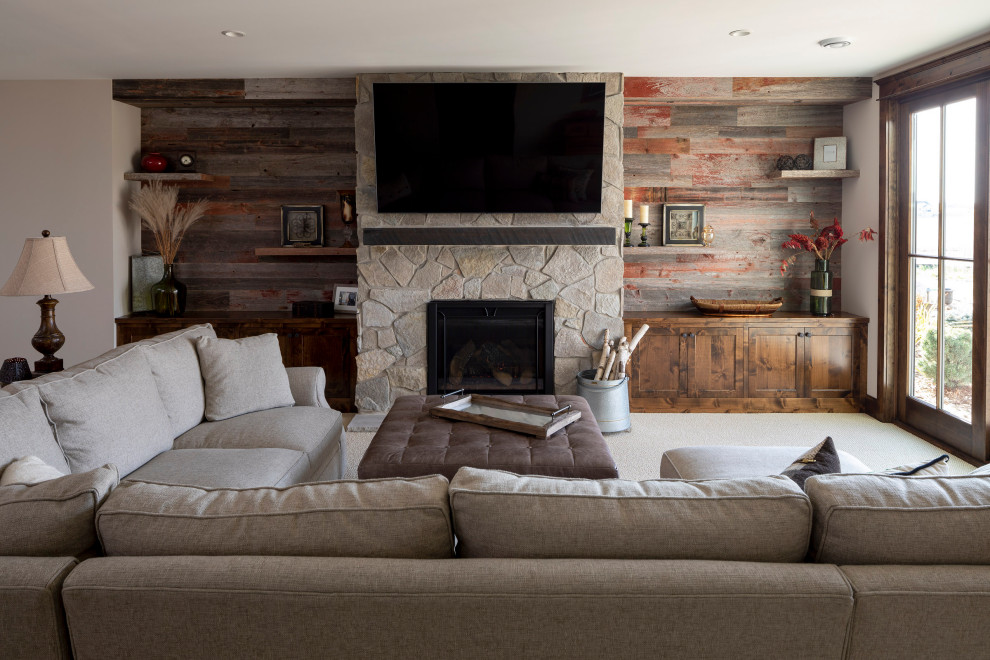Aménagement d'un grand salon montagne avec un mur beige, moquette, une cheminée standard, un manteau de cheminée en pierre, un téléviseur fixé au mur et un sol beige.
