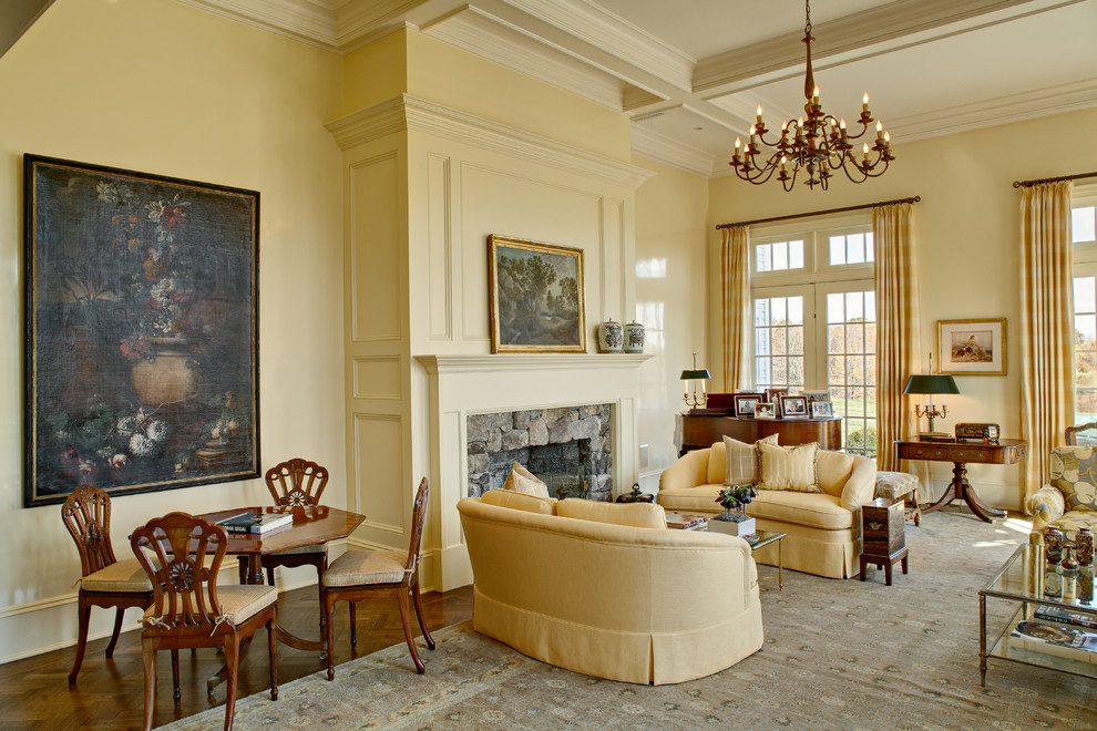 This is an example of a traditional formal open plan living room in New York with yellow walls, medium hardwood flooring, a standard fireplace, a stone fireplace surround and no tv.