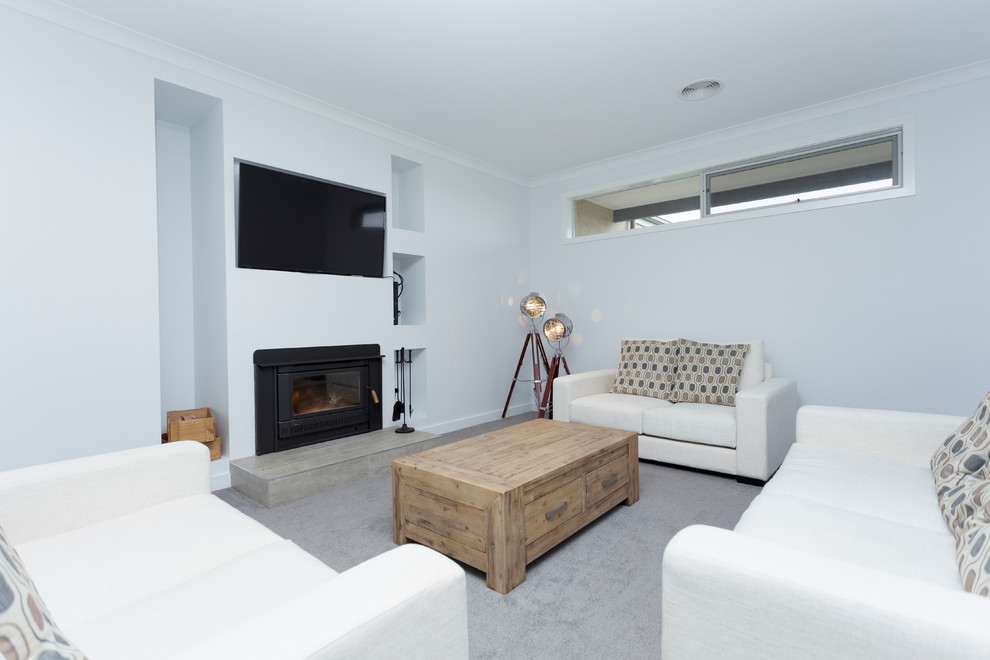 Mittelgroßes, Abgetrenntes, Repräsentatives Modernes Wohnzimmer mit weißer Wandfarbe, Teppichboden, Kamin, Kaminumrandung aus Metall, TV-Wand und grauem Boden in Melbourne