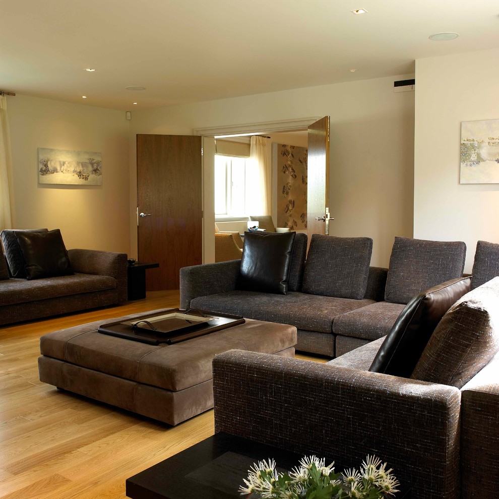Large contemporary enclosed living room in West Midlands with white walls, light hardwood flooring and a wall mounted tv.