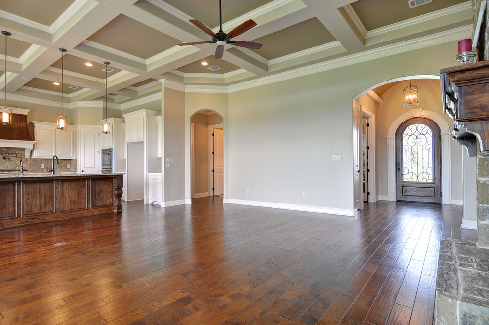 Großes, Offenes Klassisches Wohnzimmer mit beiger Wandfarbe, braunem Holzboden, Kamin und Kaminumrandung aus Stein in Dallas