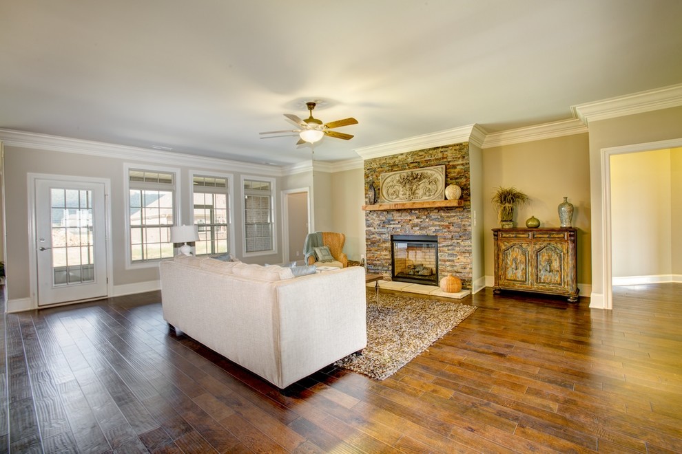 Großes, Offenes Rustikales Wohnzimmer mit beiger Wandfarbe, dunklem Holzboden, Kamin und Kaminumrandung aus Stein in Sonstige