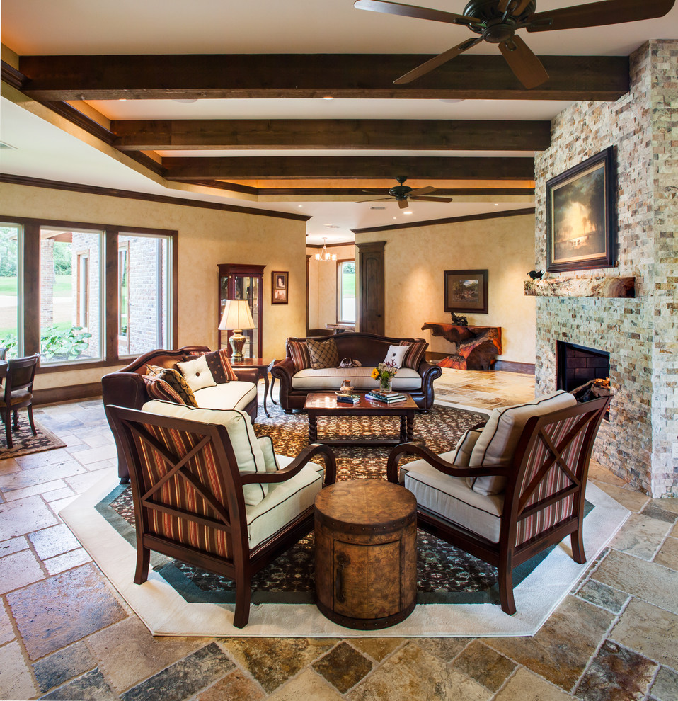 Cette image montre un grand salon traditionnel ouvert avec une salle de réception, un mur beige, un sol en calcaire, une cheminée double-face, un manteau de cheminée en pierre et aucun téléviseur.