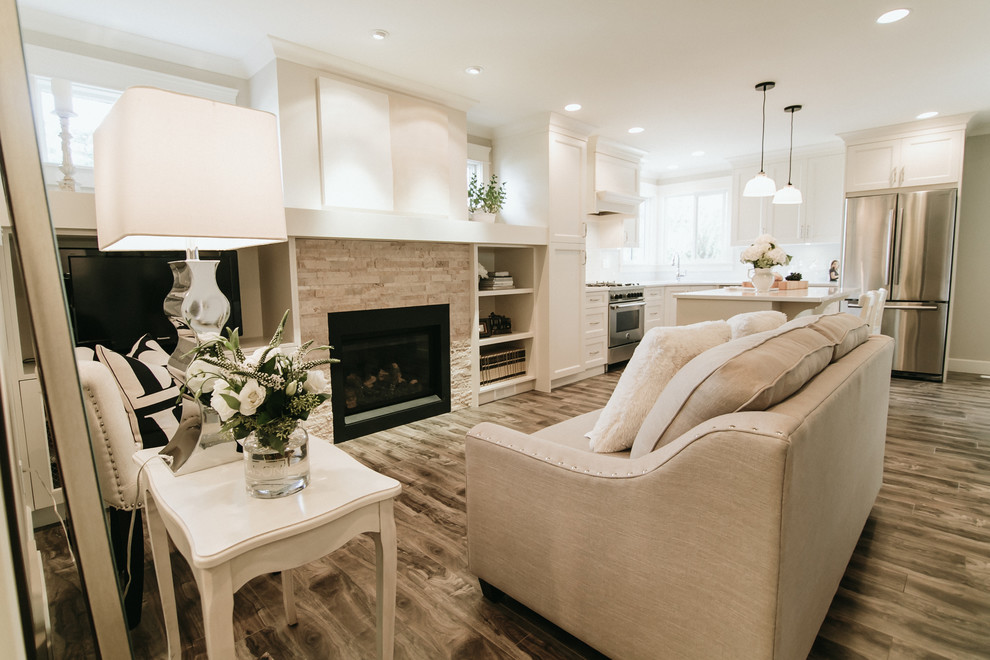 Mittelgroßes, Offenes Klassisches Wohnzimmer mit weißer Wandfarbe, dunklem Holzboden, Kamin, Kaminumrandung aus Stein, freistehendem TV und braunem Boden in Vancouver