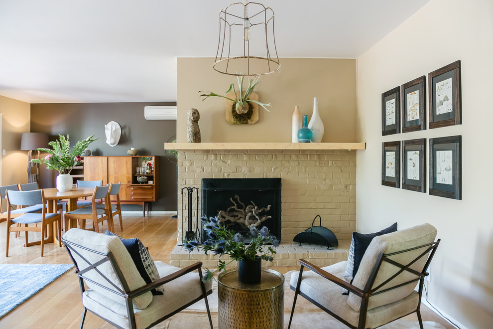 This is an example of a small midcentury living room in San Francisco with beige walls, a standard fireplace, a brick fireplace surround and feature lighting.