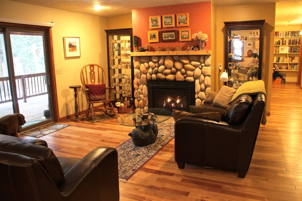 他の地域にあるお手頃価格の中くらいなラスティックスタイルのおしゃれなLDK (オレンジの壁、無垢フローリング、標準型暖炉、石材の暖炉まわり、テレビなし) の写真