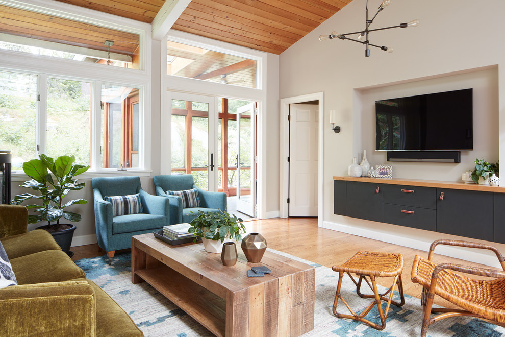 Immagine di un soggiorno classico con pareti beige, pavimento in legno massello medio e TV a parete
