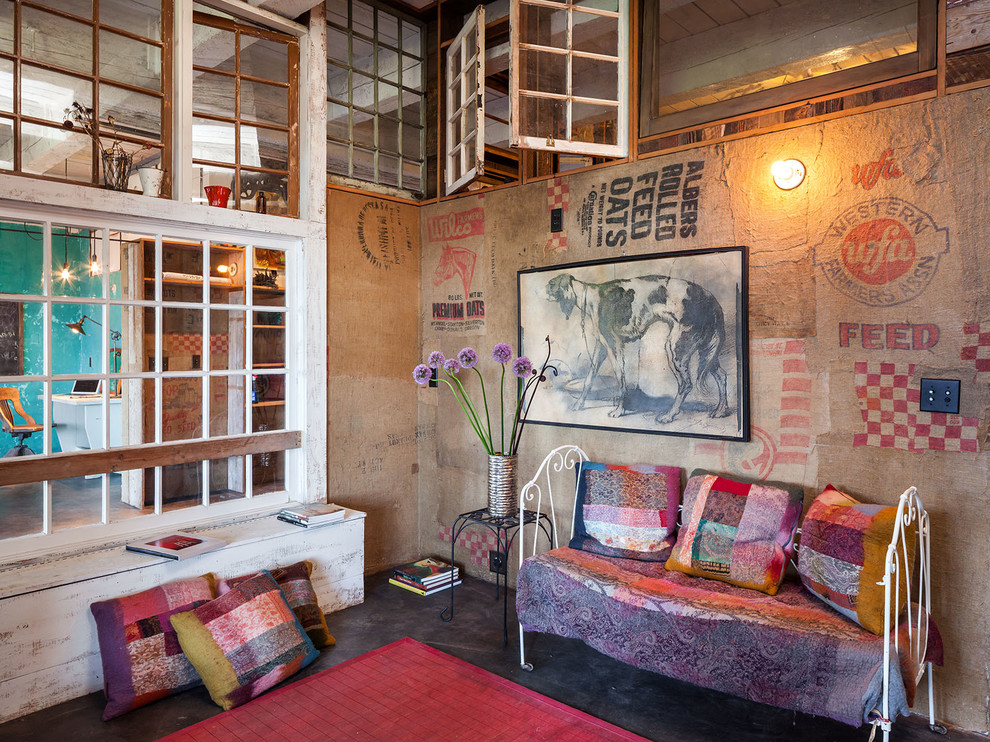 Immagine di un soggiorno boho chic con pareti multicolore, pavimento in cemento, nessun camino e nessuna TV