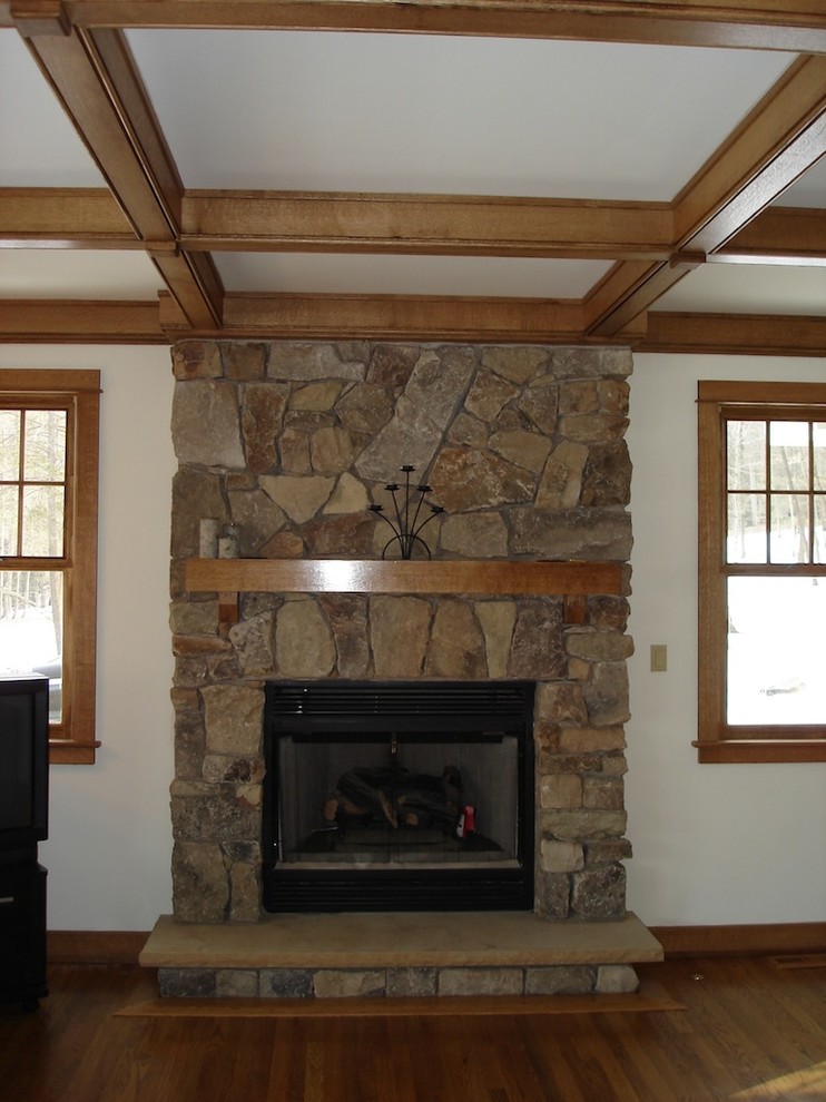 Cette photo montre un salon craftsman de taille moyenne avec un mur blanc, un sol en bois brun, une cheminée standard et un manteau de cheminée en pierre.