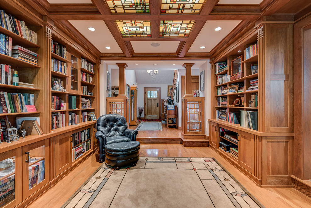 Cette image montre un grand salon craftsman ouvert avec un mur beige, parquet clair, une bibliothèque ou un coin lecture, aucune cheminée et aucun téléviseur.
