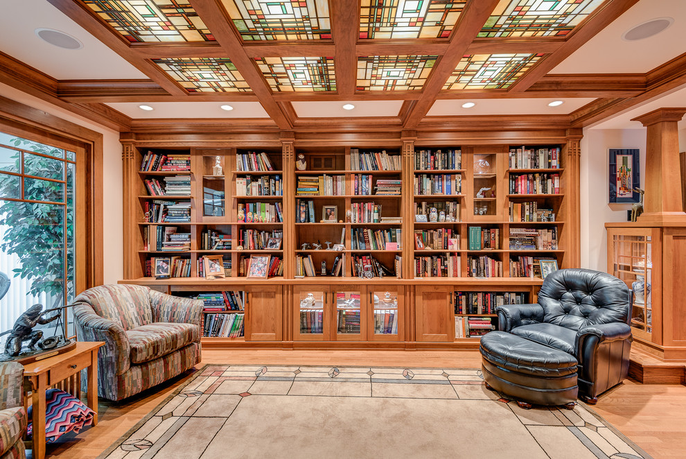 Bild på ett stort amerikanskt allrum med öppen planlösning, med ett bibliotek, beige väggar och ljust trägolv