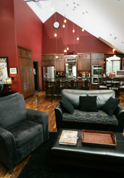 Aménagement d'un salon craftsman de taille moyenne et ouvert avec un mur rouge, un sol en bois brun, une cheminée d'angle et un manteau de cheminée en pierre.